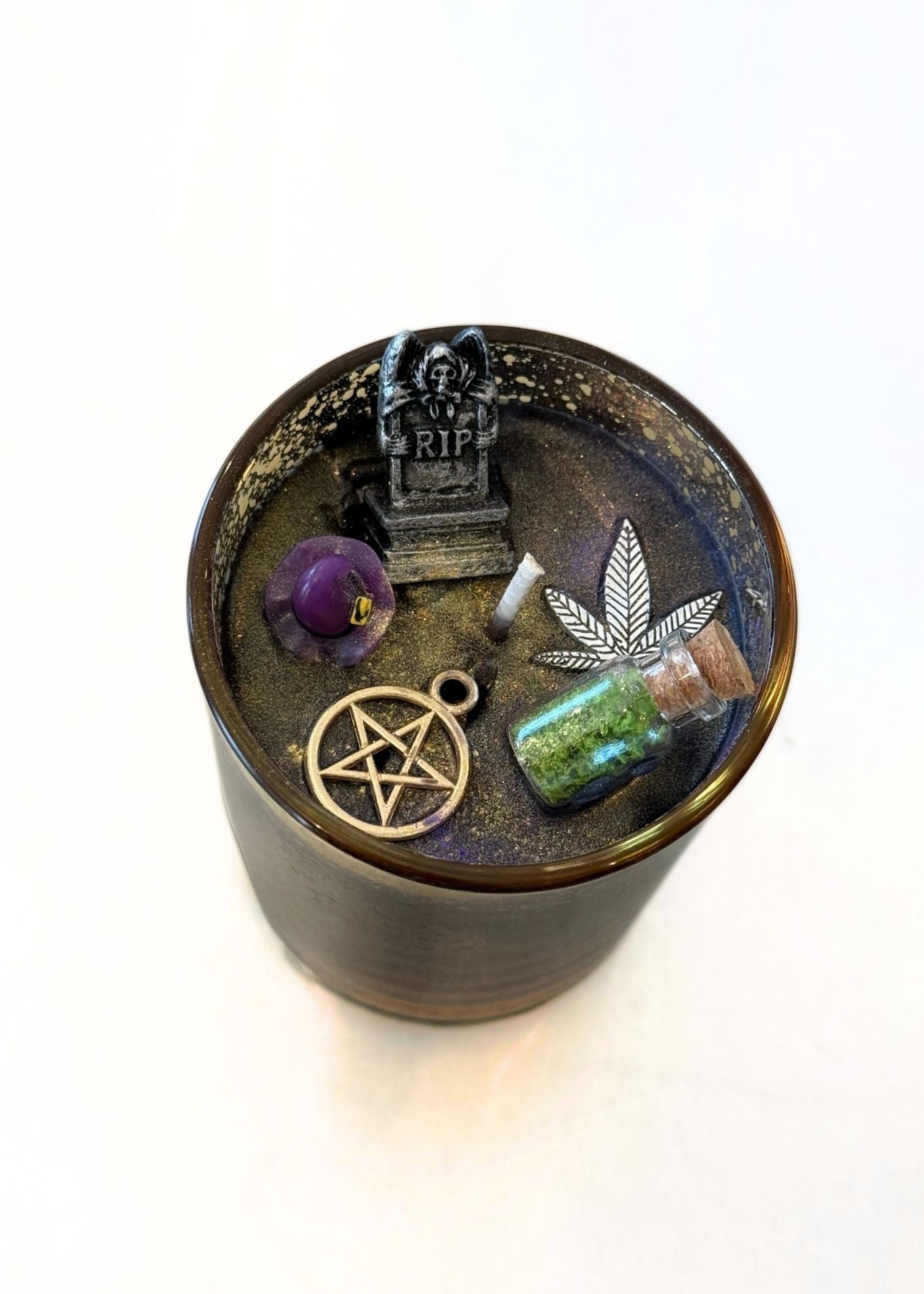 decorative candle containing multiple items in the wax, including a pentagram, crystal and more