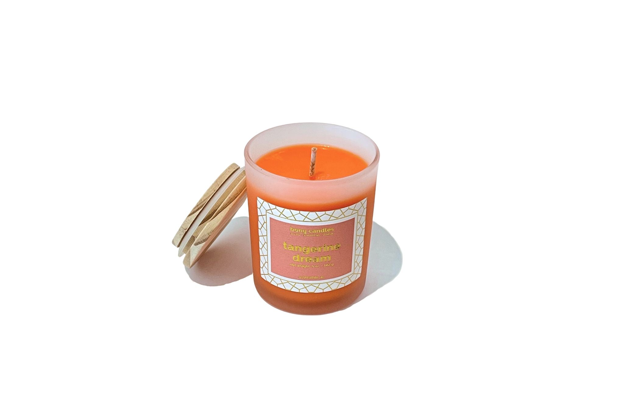 A tangerine pink soy wax candle inside a clear glass stash jar with a gold lid, labeled 'Tangerine Dream' with a decorative label.