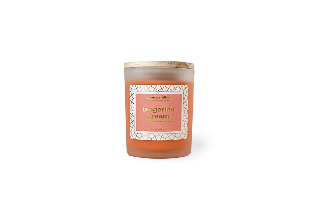 A tangerine pink soy wax candle inside a clear glass stash jar with a gold lid, labeled 'Tangerine Dream' with a decorative label.