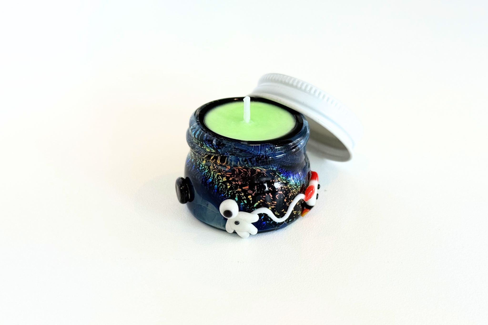 Small ceramic terp jar container with a lit candle on a white background