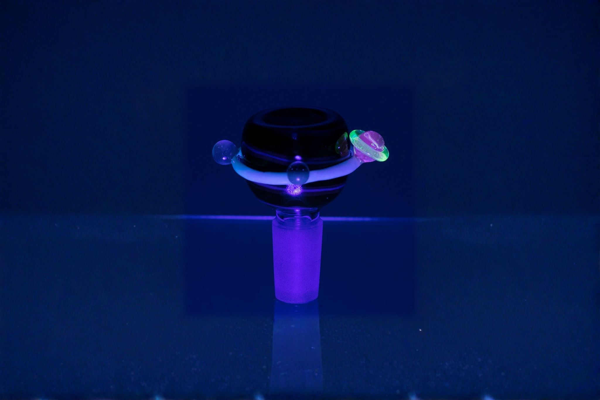 Black and purple object glowing under ultraviolet light on a dark background, custom bowl from empire glassworks x bong candles